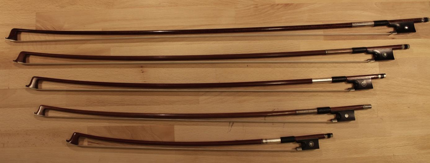 Geigenbogen in verschiedenen Grössen auf Holzuntergrund